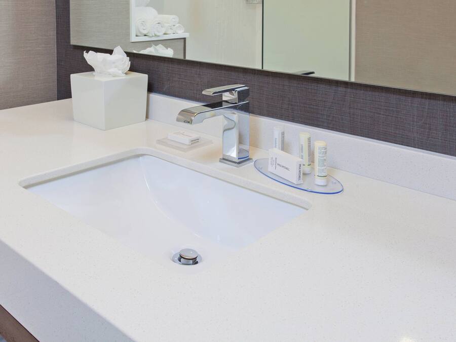 Une salle de bain moderne avec un lavabo blanc, un robinet argenté et un miroir au-dessus.