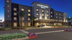 Un hotel Courtyard Marriott con un diseño moderno, que presenta una entrada cubierta y un estacionamiento.