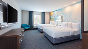 Habitación de hotel con dos camas, televisión, escritorio y ventana con cortinas.