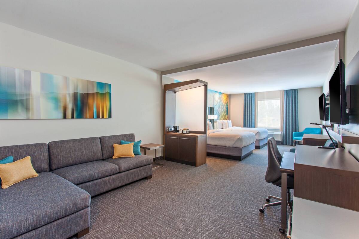 A hotel room with a sofa, a bed, a desk, and a TV.