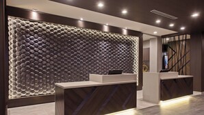 Un área de recepción de diseño moderno, con una pared con textura y un mostrador que integra una computadora.