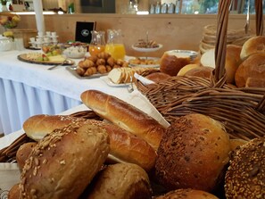 Una mesa de buffet con panes, bollería y frutas variadas.
