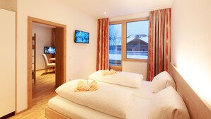 Une chambre d’hôtel avec deux lits, une télévision et une vue sur un paysage enneigé.