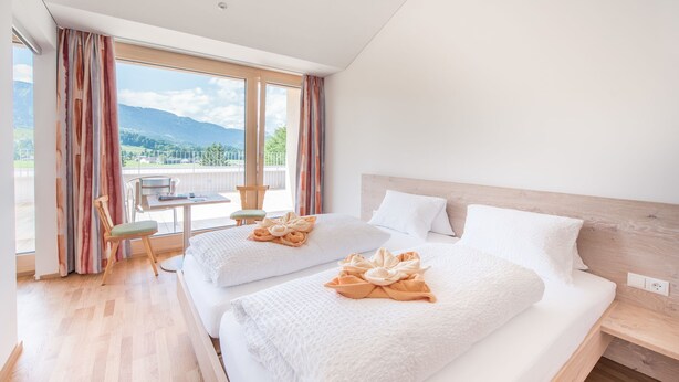 Une chambre d’hôtel avec deux lits, un balcon et une vue sur les montagnes.