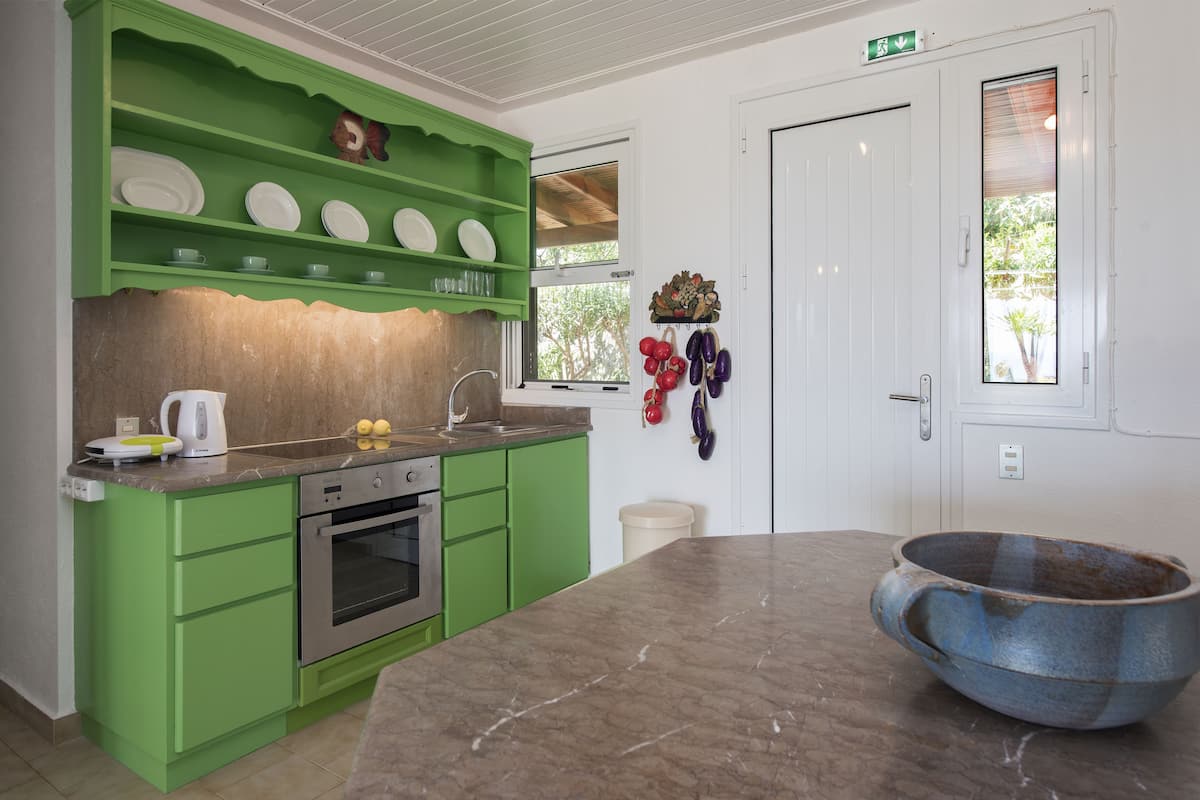 A kitchen with green cabinets, a marble countertop, and a large blue bowl.