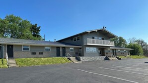 A two-story building with a parking lot in front. - Budget Inn (Cambridge)