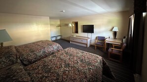 A hotel room with a large bed, a desk, a chair, a TV, and a wardrobe. - Budget Inn (Cambridge)