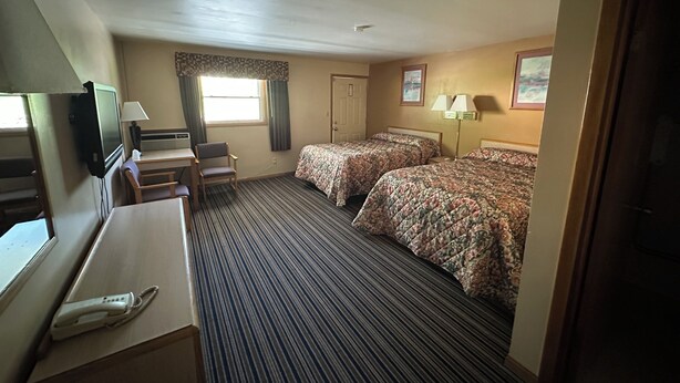 A hotel room with two beds, a desk with a telephone, a television, and a window with curtains. - Budget Inn (Cambridge)
