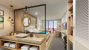 Une chambre d’hôtel moderne dotée d’un grand lit, d’une salle de bain avec un grand miroir, d’une coiffeuse avec un lavabo et offrant une vue sur la ville.