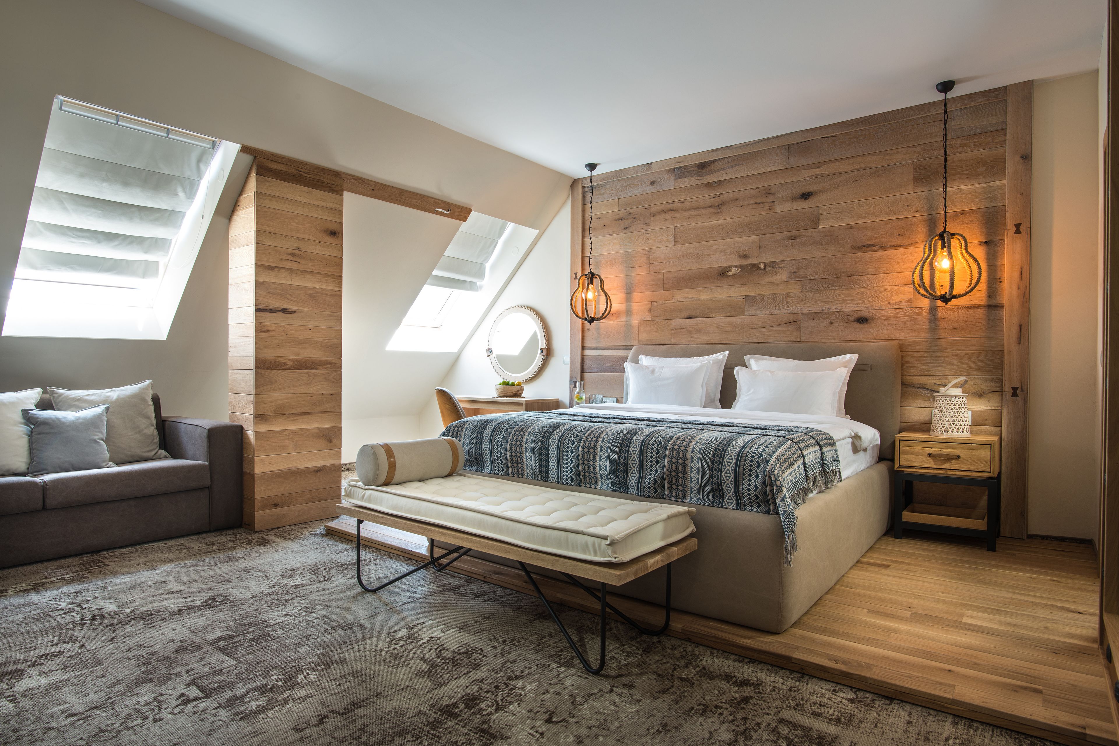 A bedroom with a loft bed, a bench, a bedside table, and a nightstand.