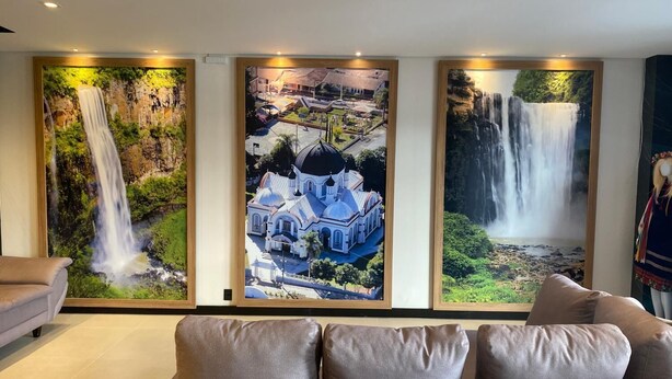 Un salón con un sofá y tres fotografías enmarcadas en la pared que muestran cascadas y un edificio.
