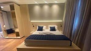Una habitación de hotel moderna con una cama grande, un armario empotrado y un espejo.