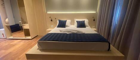 A modern hotel room with a large bed, a built-in wardrobe, and a mirror.