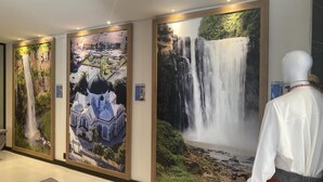 Un pasillo con tres cuadros grandes que muestran cascadas y un edificio.