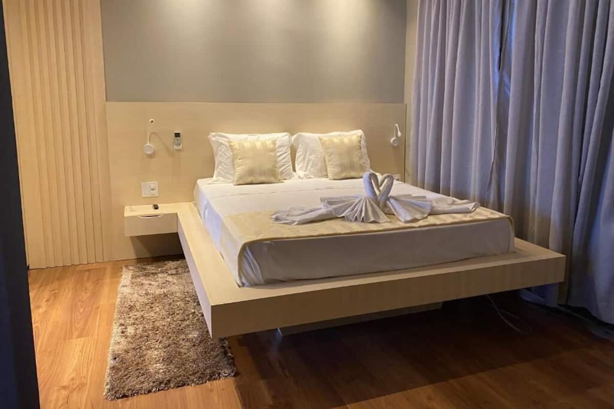 A modern hotel room with a large bed, a bedside table, and a nightstand.
