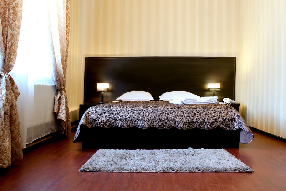 A bedroom with a large bed, two bedside lamps, a telephone, and a rug.