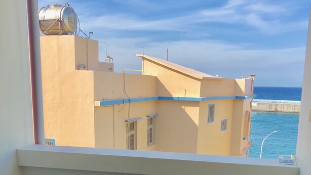 A balcony with a view of a building and the sea. - Good Things (Liuqiu)