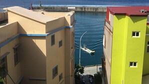 A narrow street with buildings on either side, a body of water in the middle, and a boat moving through the water. - Good Things (Liuqiu)