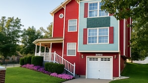A two-story house with a red and blue exterior, a front porch, and a garage.