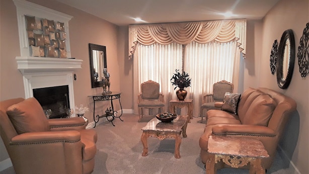 A living room with a fireplace, two armchairs, a sofa, a coffee table, and a side table.