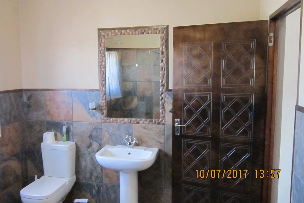 A bathroom with a toilet, sink, and a mirror.