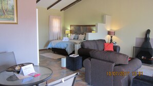 Une chambre d’hôtel avec un lit, un canapé, une petite table avec un magazine et une cheminée.