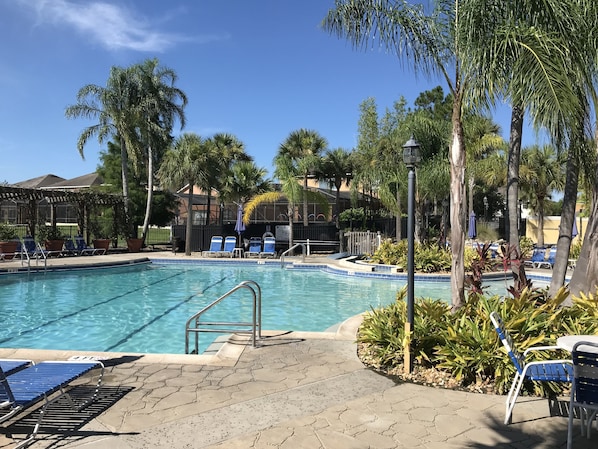 Una piscina con sillas de descanso azules y un área techada.