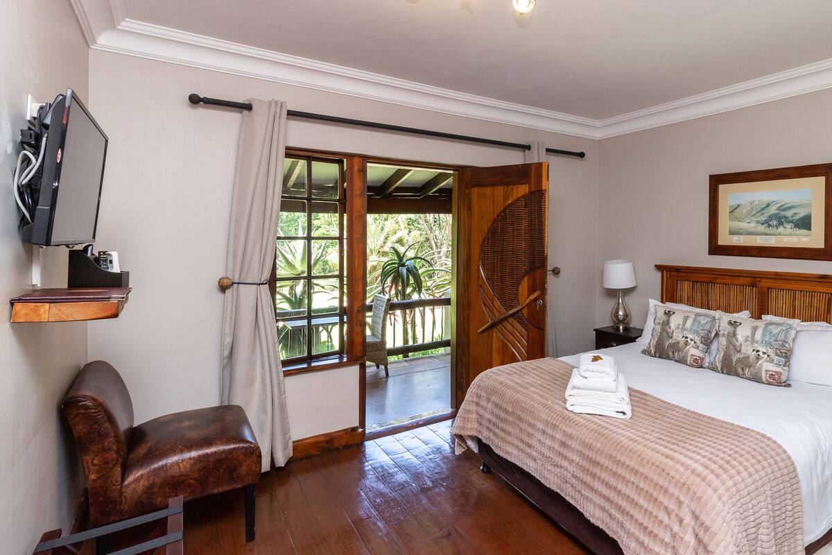 A hotel room with a bed, a desk, a chair, a television, and a window with curtains.