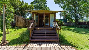 A wooden staircase leading to a covered entrance of a building, surrounded by lush greenery and a brick pathway. - Kangelani Lodge (Assagay)