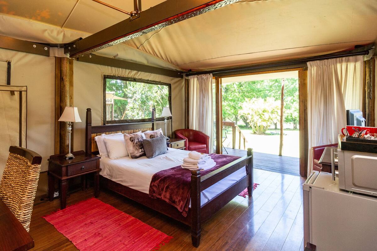 A bedroom with a bed, bedside table, lamp, and a red chair.