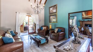 A spacious living room with leather sofas, a coffee table, and a fireplace. - Kangelani Lodge (Assagay)