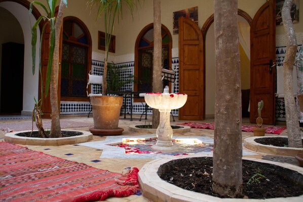 A courtyard with potted plants, a fountain, and tiled flooring. - Riad Dar Tamlil (Marrakech)