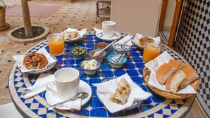 A table set with breakfast items including bread, pastries, and beverages. - Riad Dar Tamlil (Marrakech)