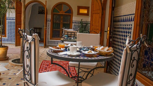 A dining area with a round table, chairs, and breakfast items. - Riad Dar Tamlil (Marrakech)