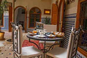A dining area with a round table, chairs, and breakfast items. - Riad Dar Tamlil (Marrakech)