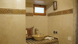 A bathroom with a checkered tile backsplash, a decorative bowl sink, a mirror with a wooden frame, and a small window above the sink. - Riad Dar Tamlil (Marrakech)
