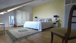 Un dormitorio con una cama, mesitas de noche, una silla, un armario y una ventana.