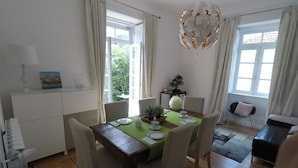 Un comedor con una mesa de madera, sillas, mantel verde y una araña.