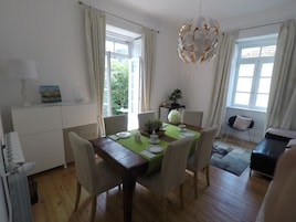 Un comedor con una mesa de madera, sillas, mantel verde y una araña.
