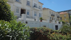 Una hilera de edificios de varios pisos con balcones, fachada blanca y cielo azul despejado.