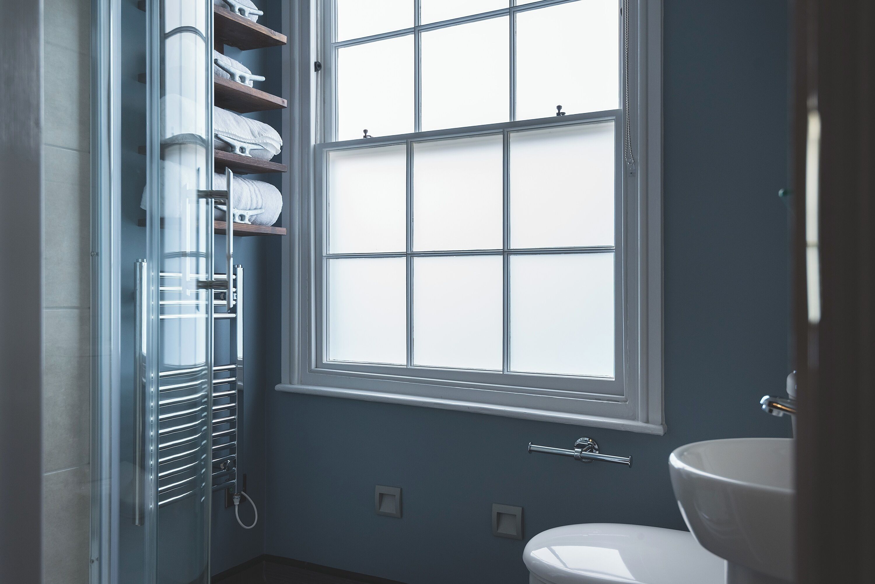 A bathroom with a window, a toilet, and a towel rack with towels.