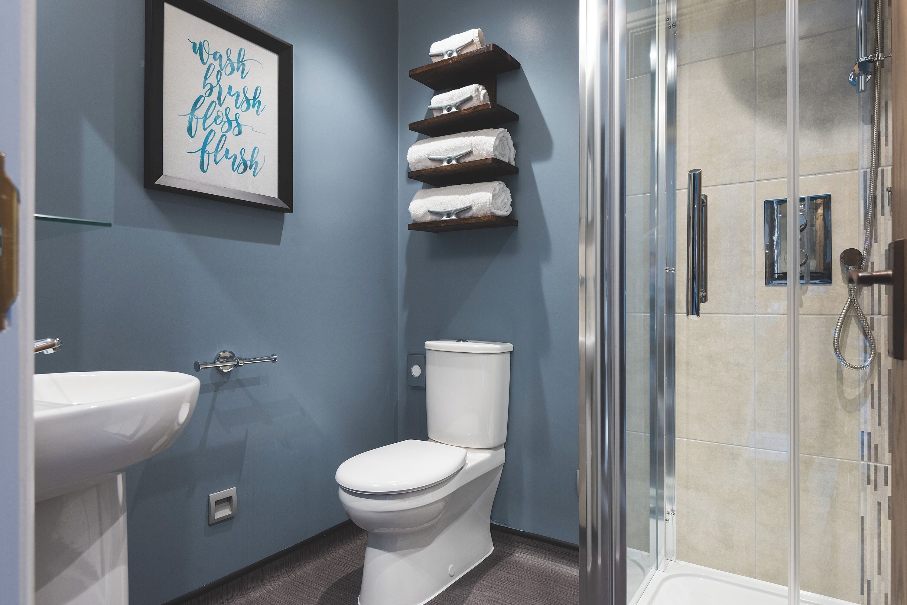 A bathroom with a toilet, sink, and a glass shower enclosure.