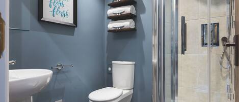 A bathroom with a toilet, sink, and a glass shower enclosure.