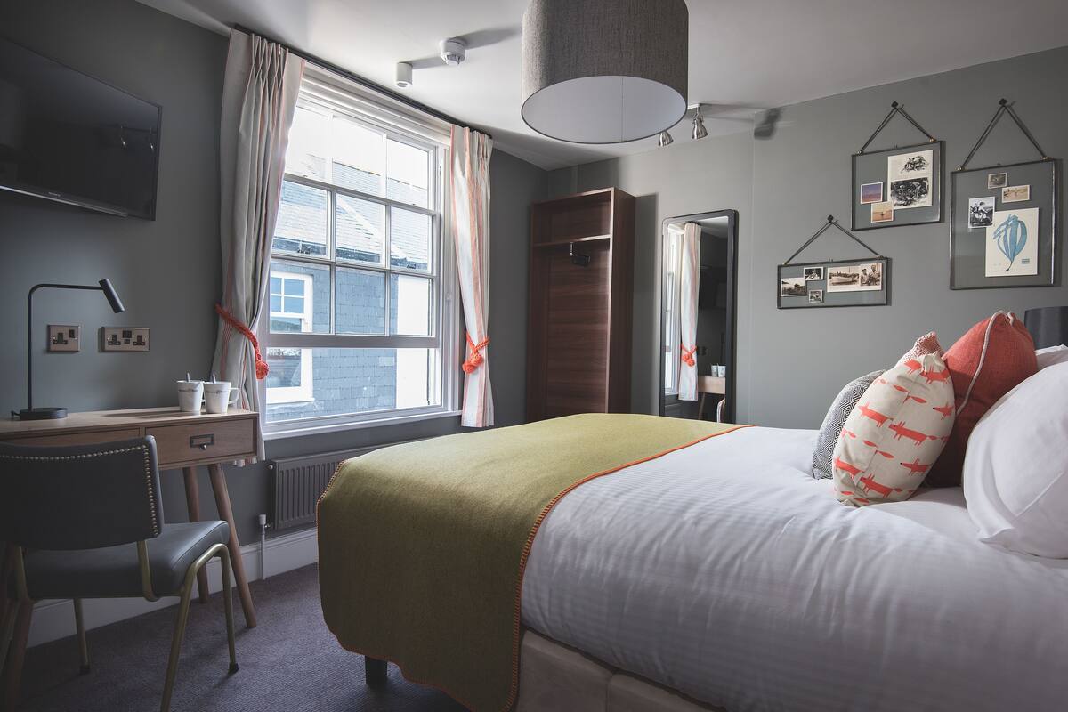 Ein ordentlich eingerichtetes Schlafzimmer mit einem Bett, einem Schreibtisch und einem Stuhl.