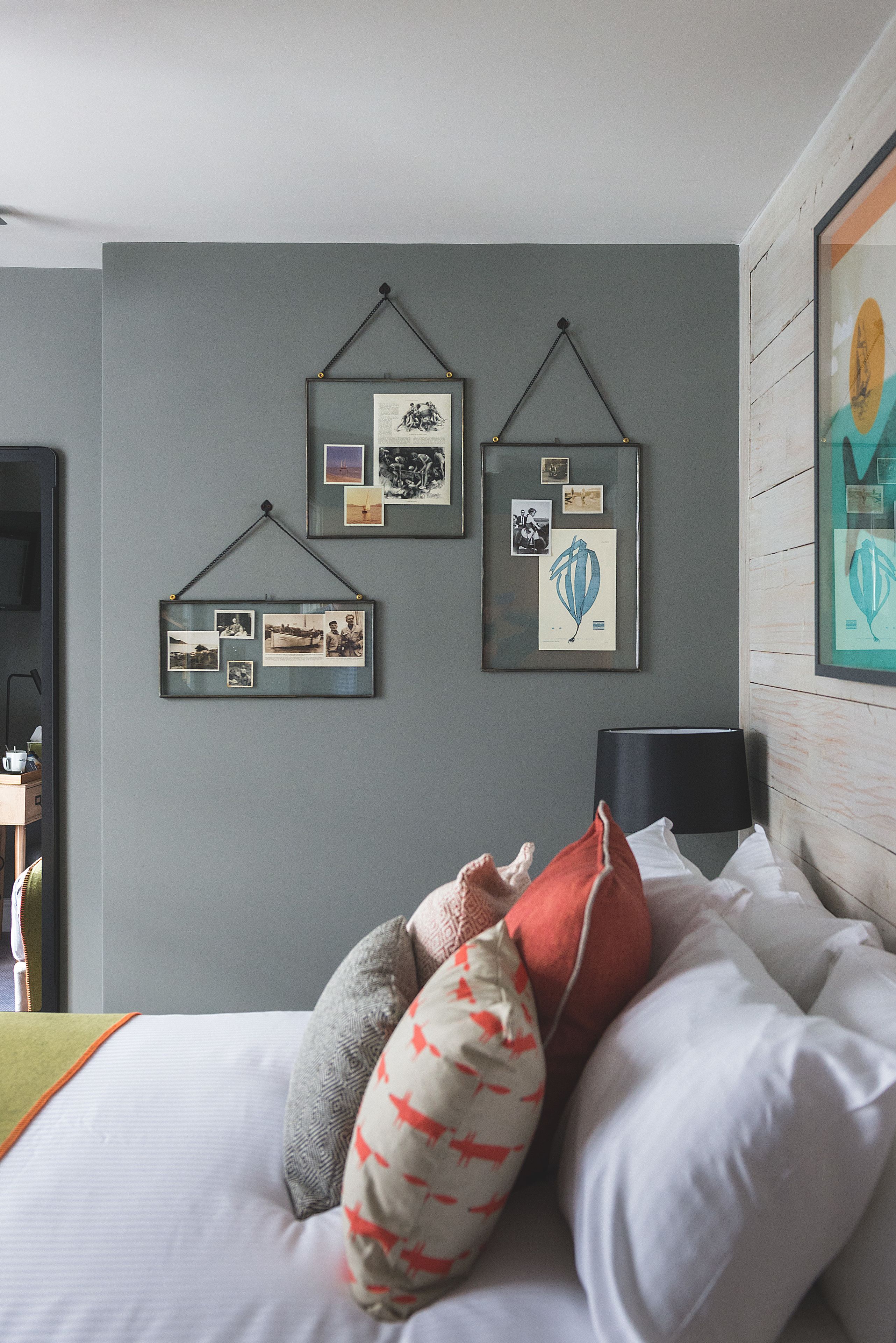 Ein Schlafzimmer mit Bett, Kissen, Nachttisch, Lampe und Wandbildern.