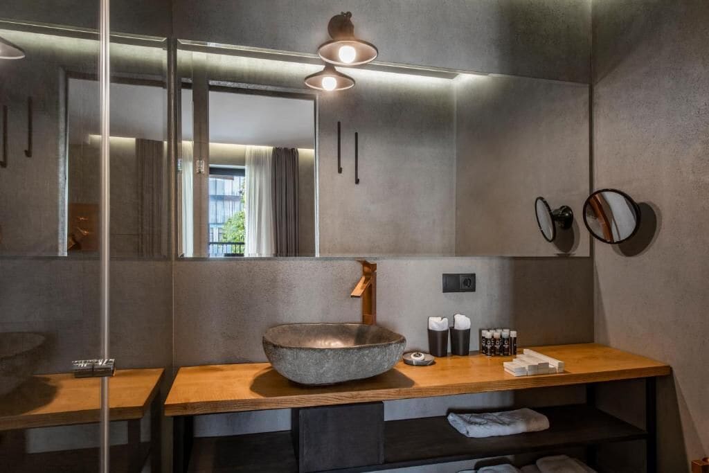Un baño moderno con un espejo grande, un tocador de madera, un lavabo de piedra y un perchero para toallas.