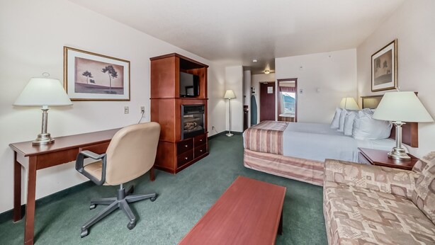 A hotel room with a desk, chair, bed, and a small sofa. - Grande Cache Inn and Suites (Grande Cache)