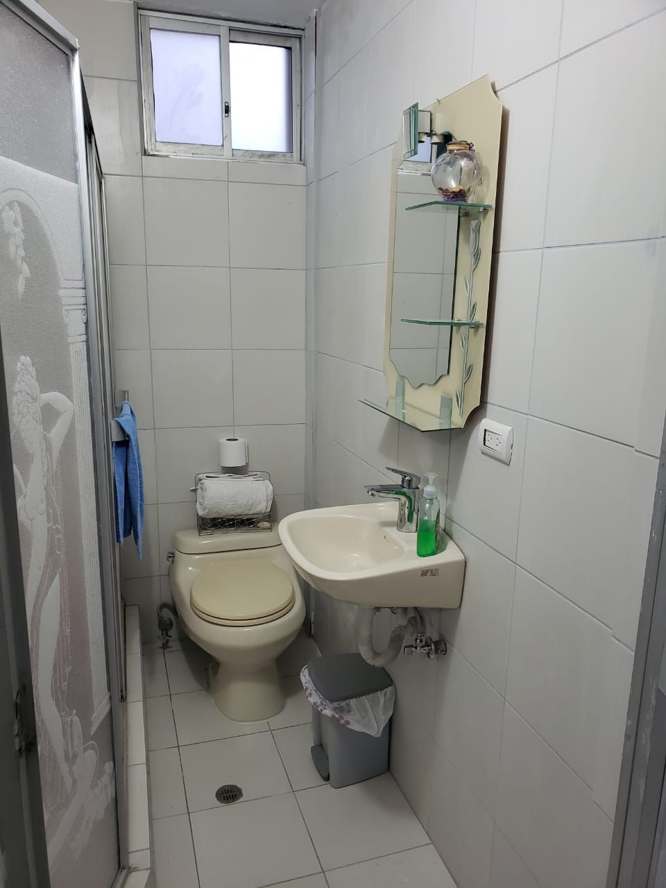 A small bathroom with a toilet, sink, and mirror.