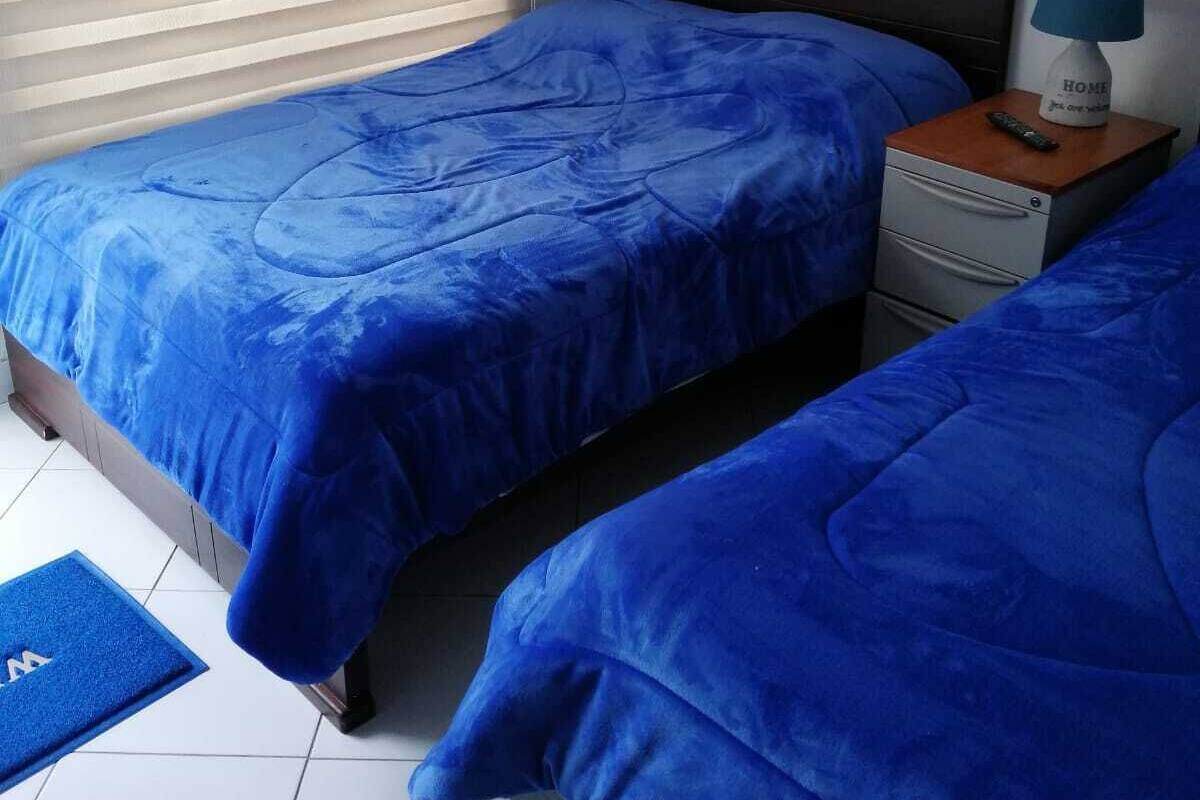 Un dormitorio con dos camas, una mesita de noche, una lámpara y un cuadro en la pared.