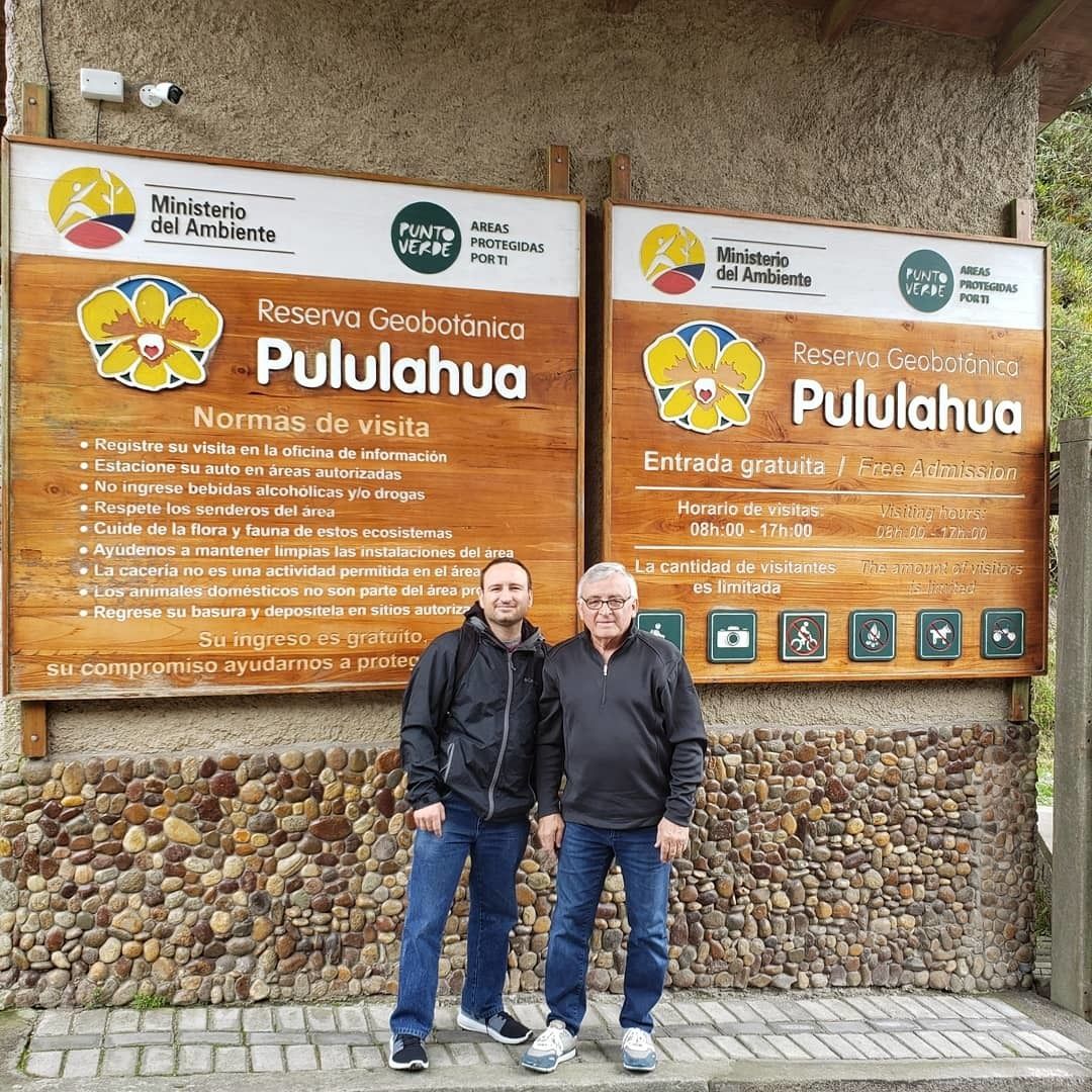 Two wooden signs with information about Pululahua Geobotanical Reserve, including visiting hours and visitor guidelines.